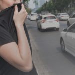 woman closes her nose with hand because of bad traffic pollution